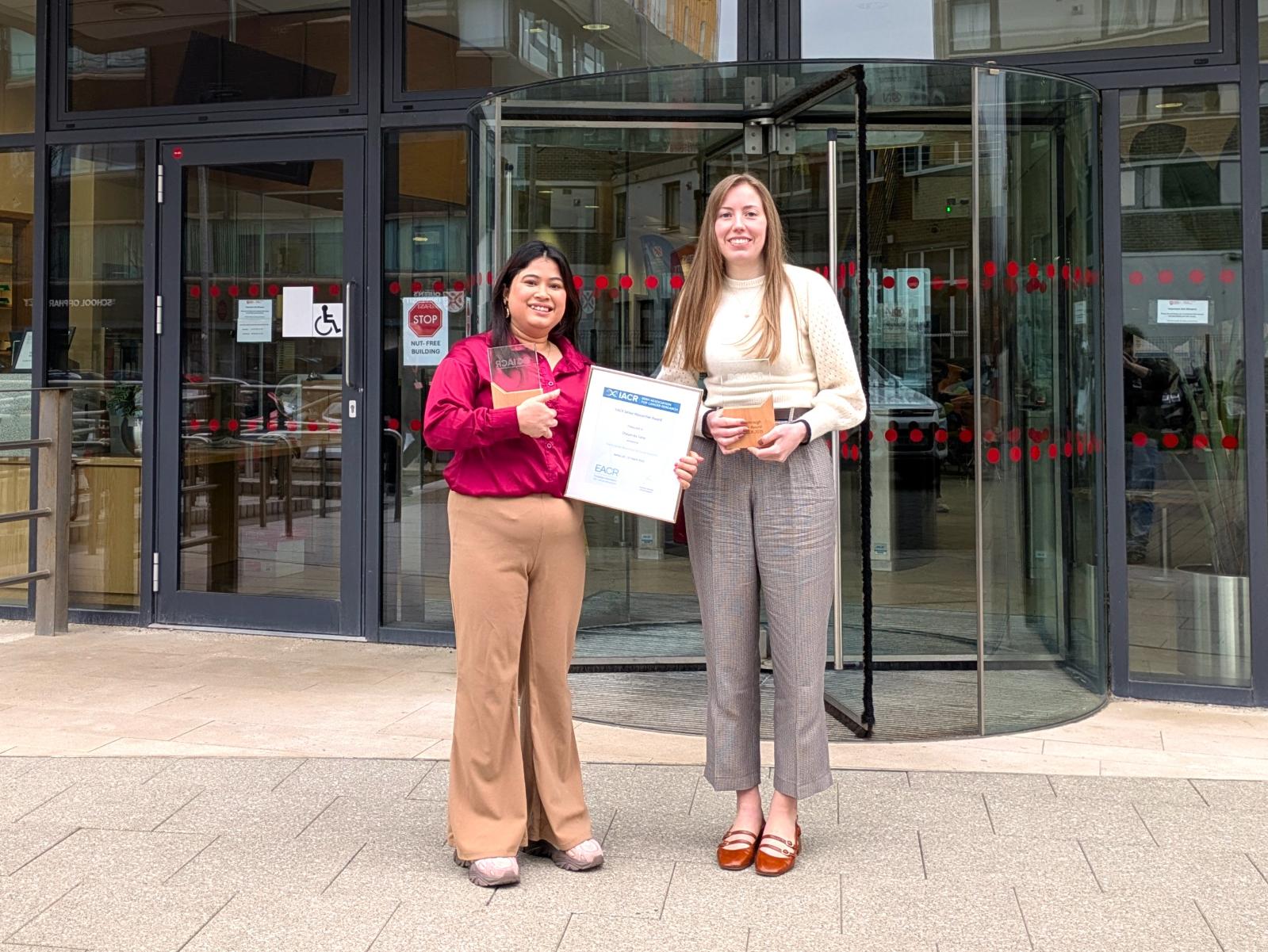 Prizewinners Chayanika Saha & Claudia Hamilton hold certificates and glass trophies